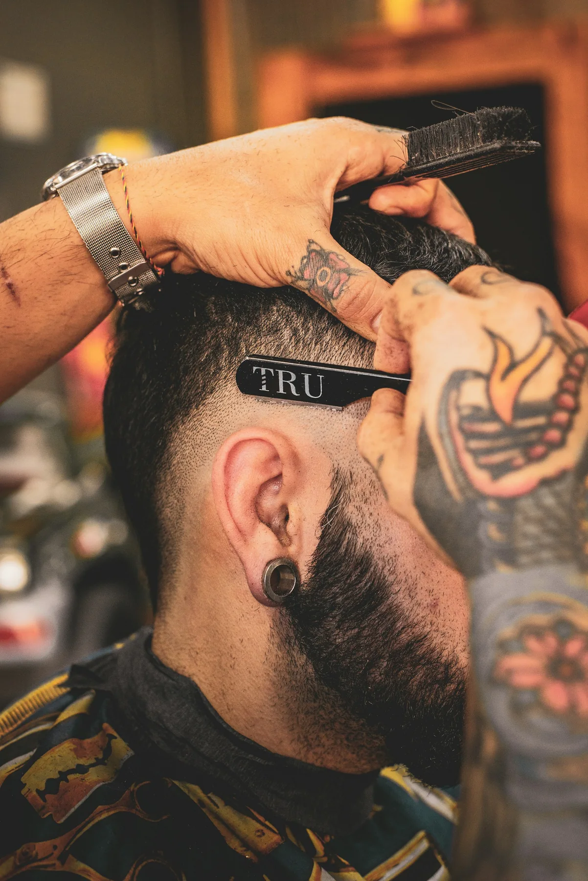 Un barbero repasa con precisión el lateral del corte de un cliente