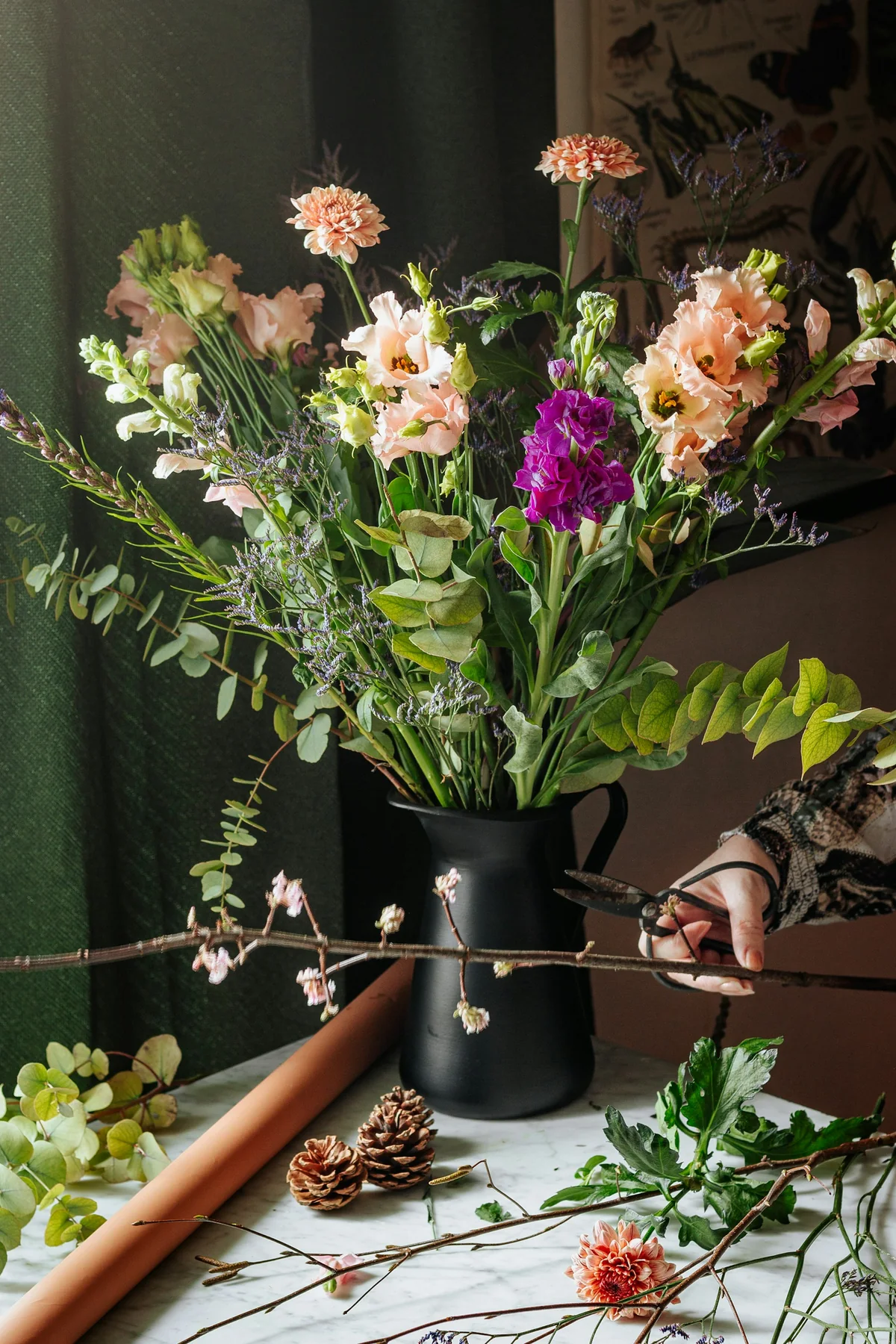 Manos de una florista preparando un ramo silvestre sobre una mesa de trabajo